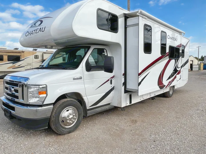 This white Chateau Class C RV rental, built on a Ford E-450 chassis, is parked with its slide-out extended.. Thor Motor Coach Chateau 2022