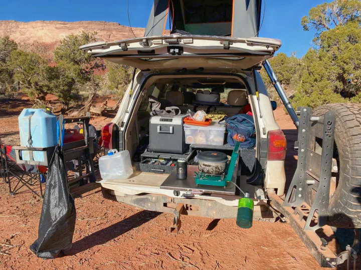 SUV's open rear for overlanding: full kitchen, fridge, and gear. Rooftop tent ready for your RV rental adventure.. Toyota Land Cruiser 2016