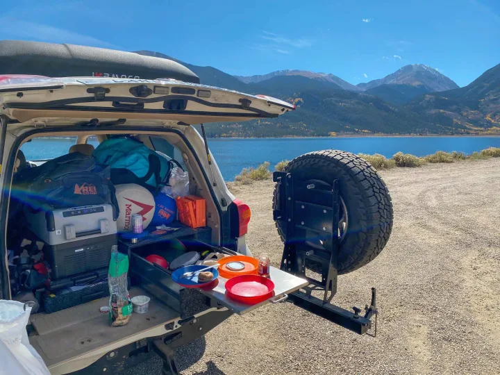 Enjoying a camping meal from this vehicle's setup by a scenic lake. Like an RV rental, it's perfect for outdoors.. Toyota Land Cruiser 2016