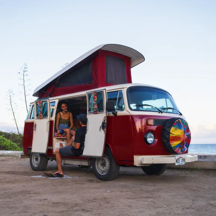 Enjoy your Hawaii RV rental! A couple relaxes in their vintage VW camper van by the ocean.. Volkswagen Other 1993