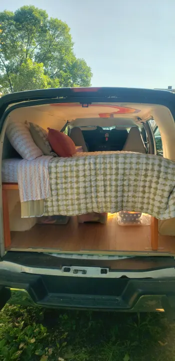 Cozy camper van interior, perfect for an RV rental or van life adventure. Bed with storage & wood floor.. Chevrolet Express 2018