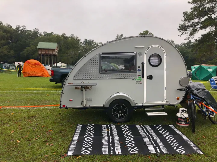 Teardrop RV rental, a nuCamp setup on grass with mat, bike, and propane for a rainy camp.. T@B T@B 320 OffRoad 2020