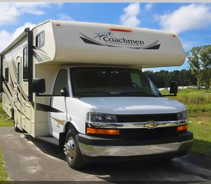 A white Coachmen Freelander Class C RV rental, featuring a Chevy chassis, parked outdoors on a paved surface.. Coachmen Freelander 2018