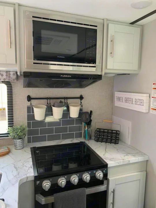 Modern RV rental kitchen with stainless appliances, light marble counters, and a dark subway tile backsplash.. Keystone Bullet 2020