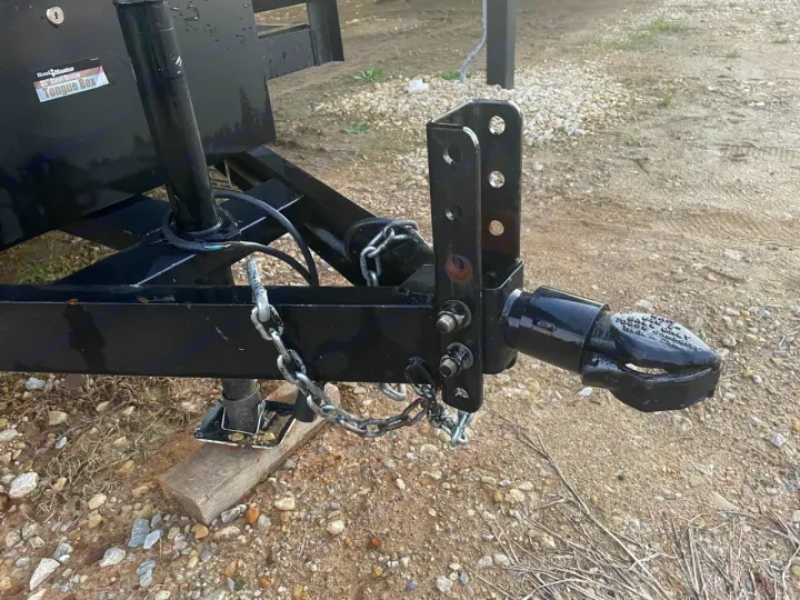 Close-up of a black trailer's adjustable pintle/ball coupler and jack assembly. Essential for secure RV rental towing.. Other Other 2020