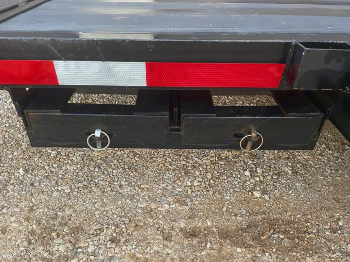 RV rental trailer's rear underbody with reflective safety tape & two black storage boxes, secured by latch pins on gravel.. Other Other 2020