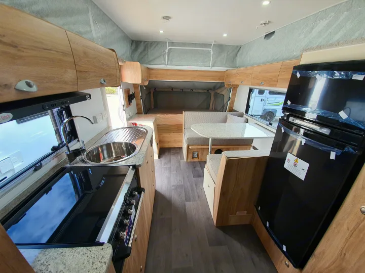 Modern rv rental interior with compact kitchen, dining area, and comfortable pop-top bed setup.. Golf Maxxi 501-1 2021