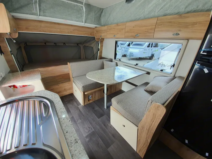 Spacious RV rental interior features dining, a compact kitchenette with sink, and a bed in the pop-up section.. Golf Maxxi 501-1 2021