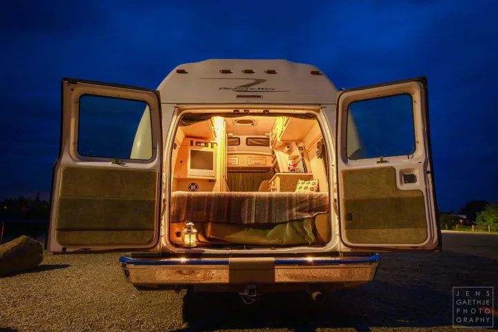 Open back doors reveal a cozy Pleasure-Way rv rental interior at night, ready for your next adventure.. Ford FordE350 2006
