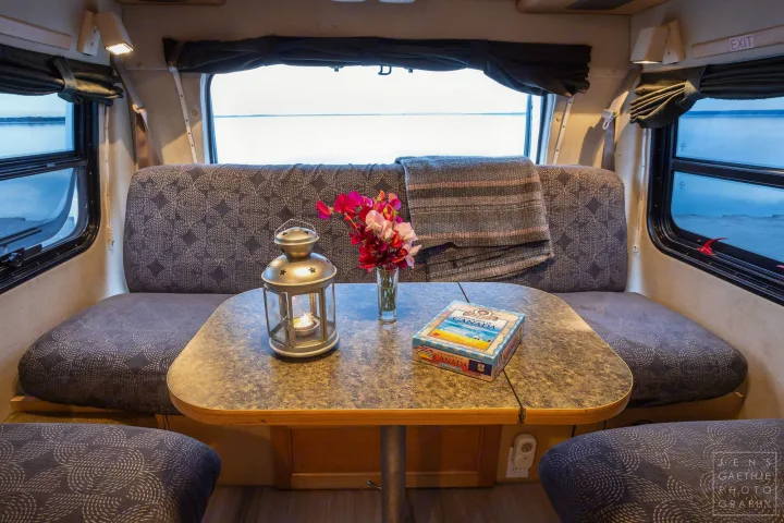 Cozy RV rental interior with dining area, flowers, and "Geography of Canada" game, overlooking a scenic lake.. Ford FordE350 2006