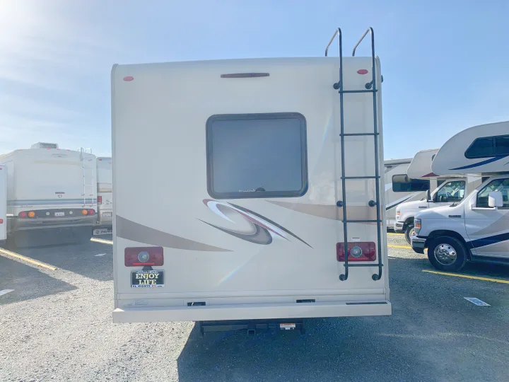 Rear view of an RV rental, highlighting its roof ladder, central window, and "Enjoy Life" message. Ready for your next trip!. Thor Motor Coach Four Winds 2020