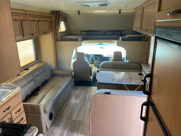Explore this cozy RV rental interior: lounge sofa, dinette, kitchen, & bunk, perfect for road trip comfort.. Thor Motor Coach Four Winds 2020