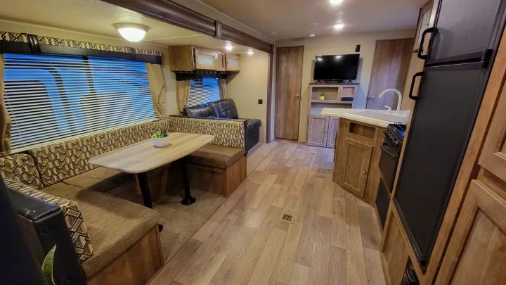 Inside this spacious RV rental: a bright living space with dinette seating, full kitchen, and entertainment center.. Forest River Puma 2017