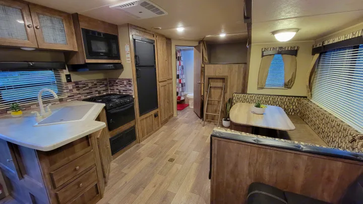 Interior of a modern RV rental, featuring a full kitchen, dinette, bathroom, and bunk beds. Ideal for travel trailer trips.. Forest River Puma 2017