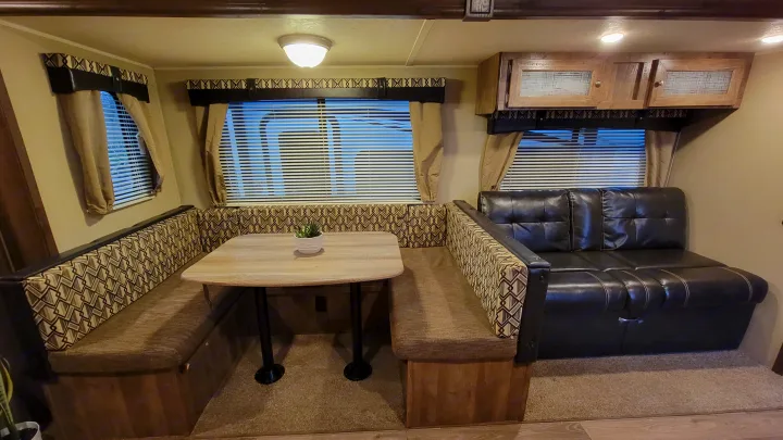 Cozy RV rental interior features a spacious dinette with U-shaped seating, a table, and a comfortable sofa.. Forest River Puma 2017