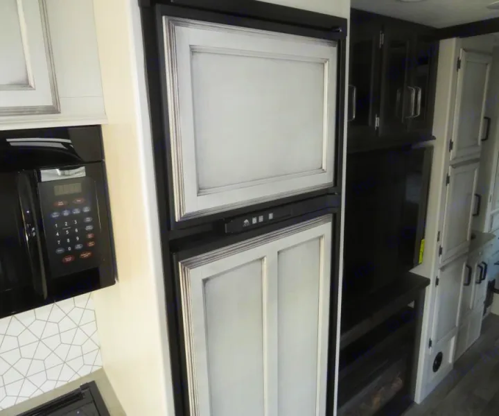Modern RV rental kitchen & living space, featuring a paneled refrigerator, microwave, and stylish light/dark cabinetry.. Entegra Coach Odyssey 30Z 2022