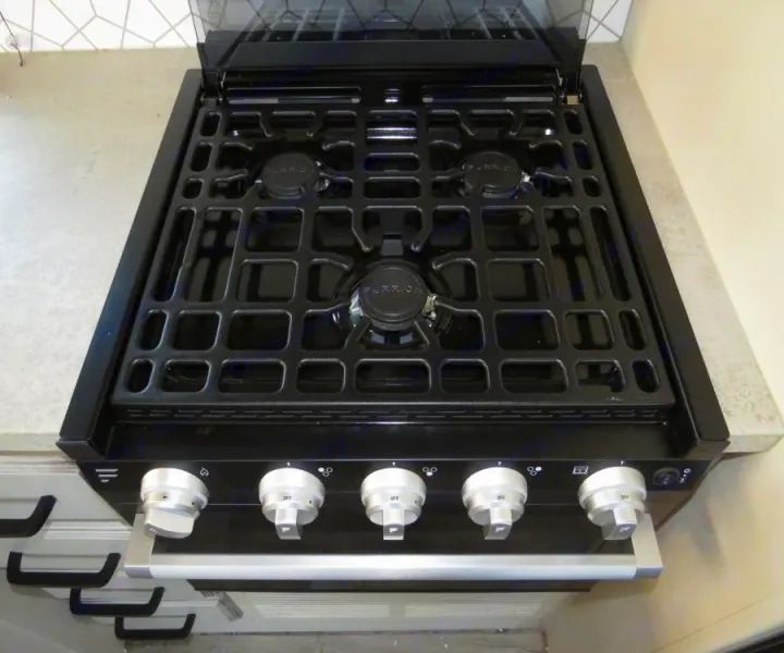 Close-up of a modern black Furrion gas range and oven in an RV rental kitchen.. Entegra Coach Odyssey 30Z 2022
