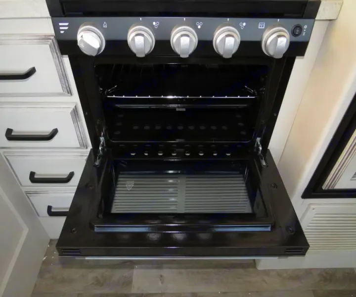 Clean, open oven/stove in an RV rental kitchen, showing interior, racks, and top controls.. Entegra Coach Odyssey 30Z 2022
