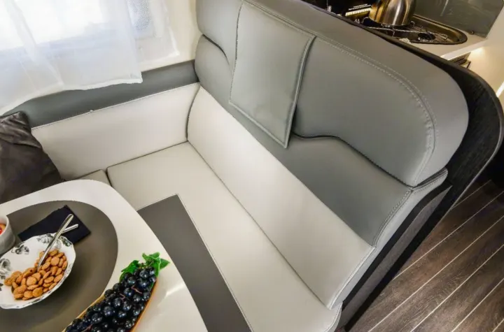 RV rental dinette: a modern interior with two-tone grey & cream seating, a dining table with fruit, and wood flooring.. Roller Team 685 Zefiro 2022