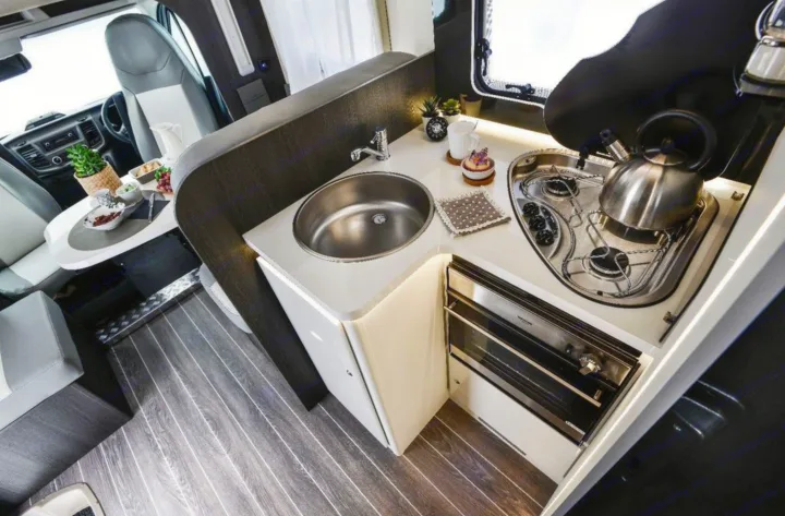 Compact RV rental interior: modern kitchen with sink, stove, oven, and dining nook. Ready for your travels.. Roller Team 685 Zefiro 2022