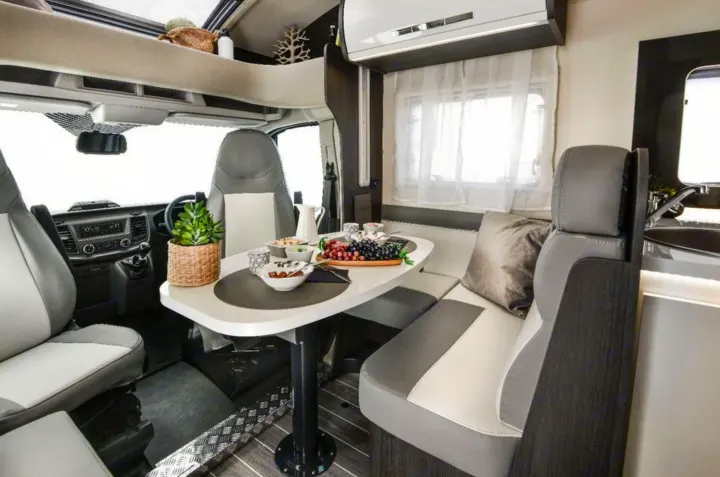 Experience a comfortable RV rental! This campervan interior showcases a modern dining area, kitchenette, and driver's cabin.. Roller Team 685 Zefiro 2022