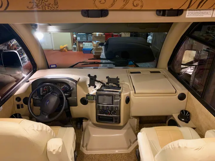 Spacious RV rental cockpit view from inside, showing a Ford steering wheel, light-colored dash, and front seats.. Thor Vegas 2016