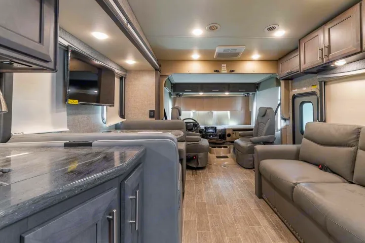 Spacious RV rental interior: living area with sofa & dinette, kitchen, and cockpit. Perfect for road trips.. Thor Motor Coach Outlaw 2022