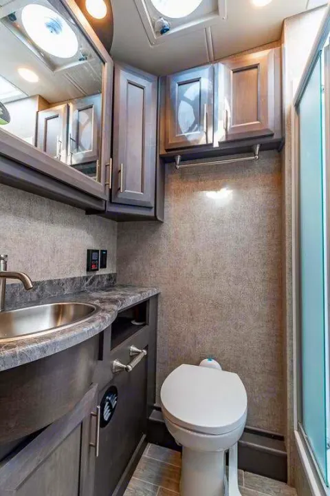 RV rental bathroom: sink, toilet, sleek cabinets, and a shower, providing home-like comfort for your travels.. Thor Motor Coach Outlaw 2022