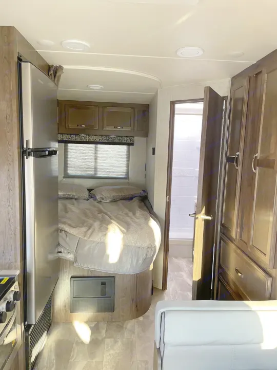 RV rental interior: inviting bedroom, compact kitchen with fridge, and bright bathroom. Your comfortable home on wheels.. Gulf Stream Conquest 2021