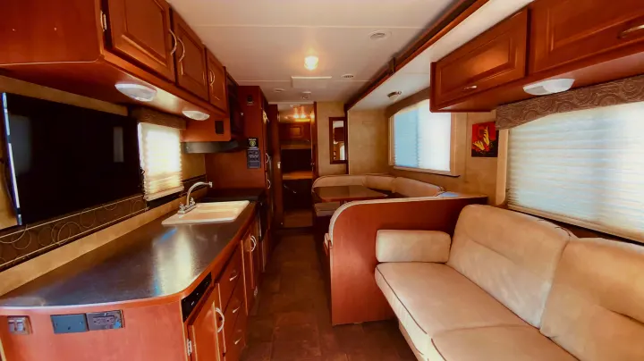 Spacious RV rental interior: kitchen with sink, dinette, and sofa offer a comfortable living area for travel.. Winnebago 31k 2015