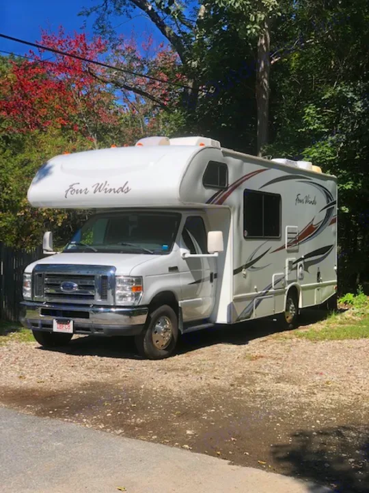 A white Four Winds Class C RV rental is parked on a sunny day, ready for travel or camping.. Four Winds Four Winds Motorhome 2011