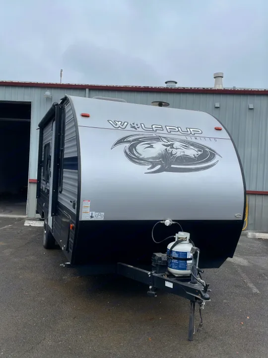 A grey Wolf Pup travel trailer, featuring propane tanks & hitch, ideal for your next RV rental adventure.. Forest River Cherokee Wolf Pup 2019