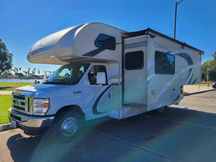 A white Chateau Class C rv rental, a Ford E-350 motorhome with slide-out, parked by the water. Perfect for travel!. Thor Chateau 2018