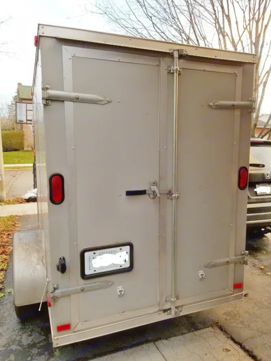 Rear view of a rented enclosed grey cargo trailer, useful for hauling and often found at RV rental services.. Other Other 2012