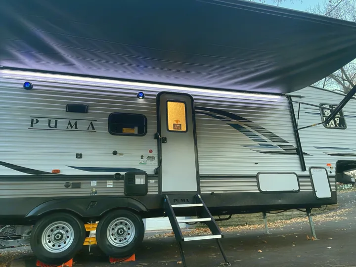 This PUMA travel trailer, great for rv rental, features an illuminated awning, blue lights, and extended steps.. Palomino Puma 2022