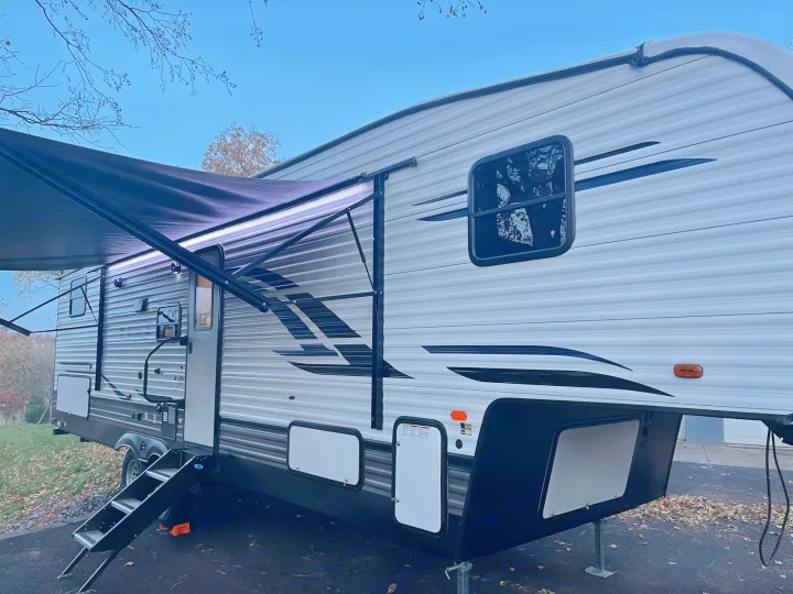 Experience outdoor living! This white and grey travel trailer RV rental features an extended awning with bright LED lights.. Palomino Puma 2022