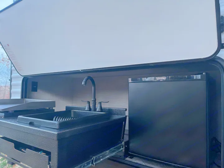 This RV rental outdoor kitchen features a pull-out sink, griddle, and an Ever Chill mini-fridge.. Palomino Puma 2022
