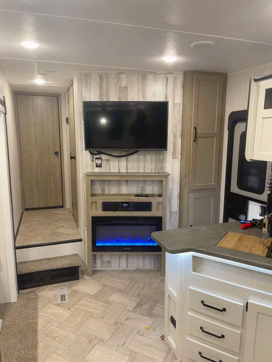 Discover this modern RV rental's inviting interior: living area with TV/fireplace, well-designed kitchen island, and steps to the bedroom.. Palomino Puma 2022