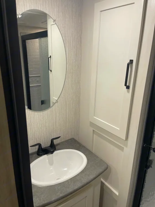 Well-designed compact RV bathroom with an oval sink, modern black faucet, mirror, and storage cabinet, perfect for rv rental.. Palomino Puma 2022