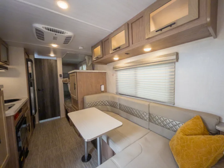 Bright rv rental interior: U-shaped dinette, functional kitchen, overhead cabinets, and AC. Ready for comfortable travels!. Forest River NOBO 19.7 2022