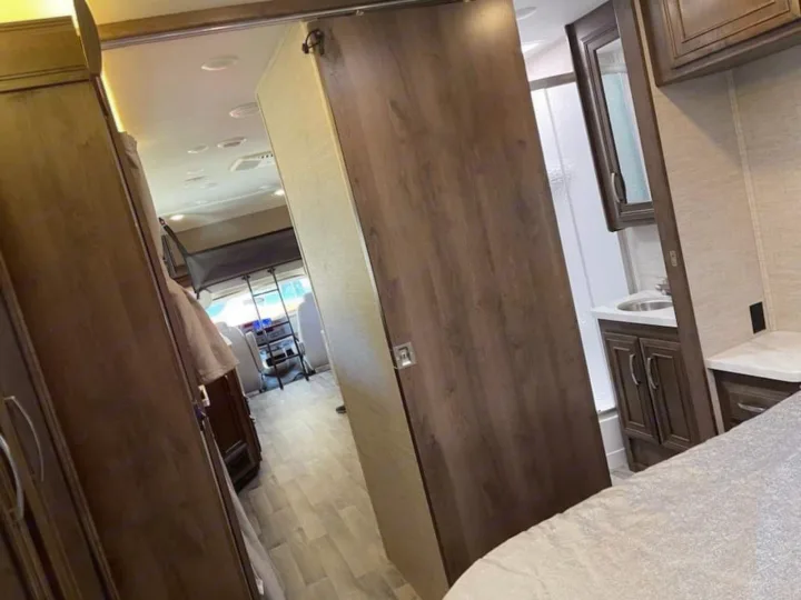 Spacious RV rental interior: bedroom foreground, sliding door separating it from the bathroom and front living area.. Ford Ford 2022