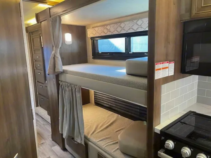 Experience comfort in this RV rental! Features include stacked bunk beds with windows, privacy curtains, & a kitchen area.. Ford Ford 2022