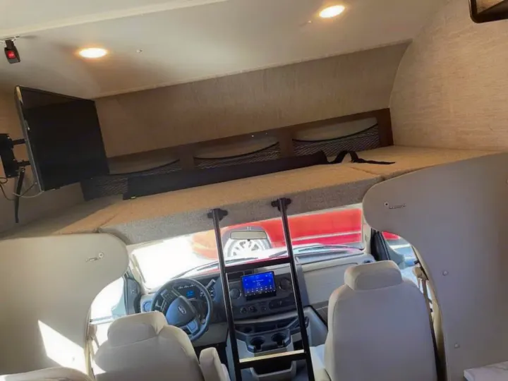 Cozy RV rental interior: large overhead bunk with TV, plus driver's cockpit. Ready for travel!. Ford Ford 2022