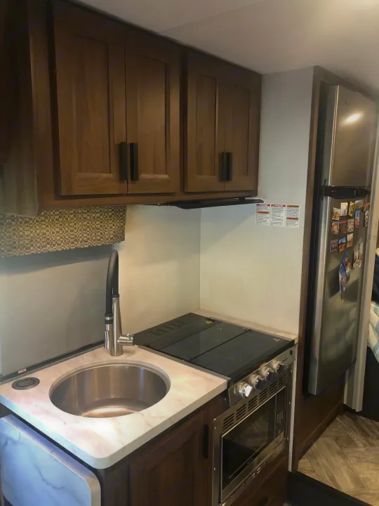 Compact kitchen in an RV rental, featuring a sink, cooktop, microwave, and fridge, ideal for travel.. Forest River Other 2021