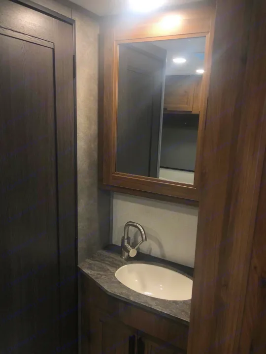 Inside an RV rental: a modern bathroom vanity with dark wood accents, white oval sink, and chrome faucet.. Forest River Other 2021