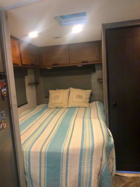Comfortable RV rental sleeping area with bright lights, overhead storage, and beach-themed pillows.. Forest River Other 2021