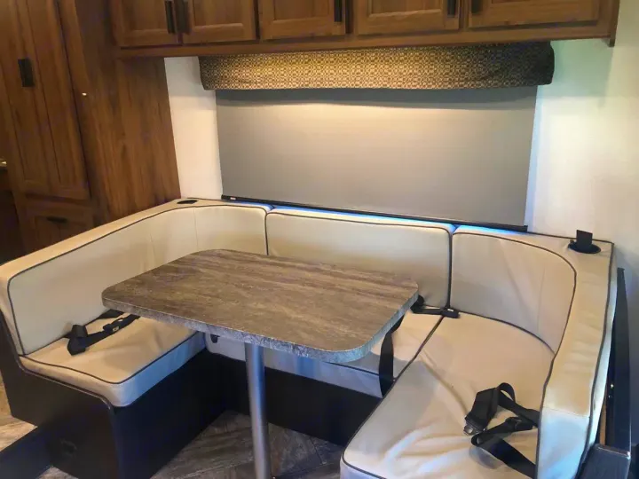 Comfortable U-shaped dinette in an RV rental, featuring a table, plush cushions, and overhead cabinets.. Forest River Other 2021