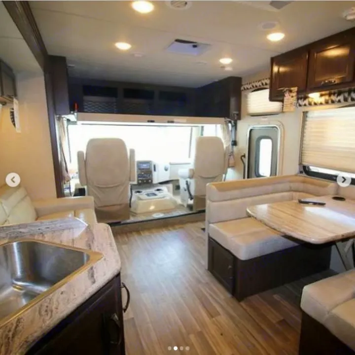 Spacious RV rental interior featuring a bright driver's cockpit, comfortable dinette, and compact kitchen area.. Thor A.C.E. 2018