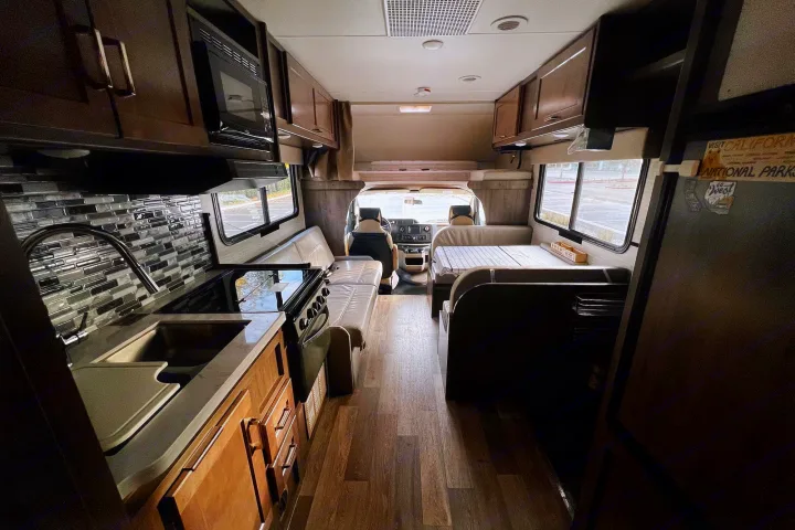 Explore this RV rental's inviting interior, featuring a full kitchen, dinette, and sleeping bunk.. Winnebago Spirit 2020