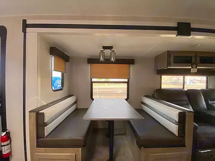 An inviting RV rental interior, featuring a practical dinette with two cushioned benches and a sturdy central table.. Palomino Puma 31-RLQS 2022